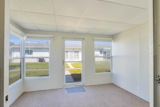 doorway with a sunroom, carpet floors, plenty of natural light, and a paneled ceiling