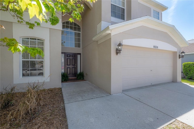 entrance to property featuring concrete driveway and stucco siding