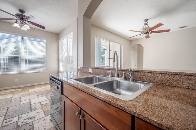 kitchen with arched walkways, black dishwasher, stone tile floors, visible vents, and a sink