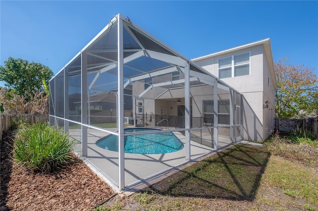 back of house featuring a fenced in pool, stucco siding, glass enclosure, a patio area, and a fenced backyard