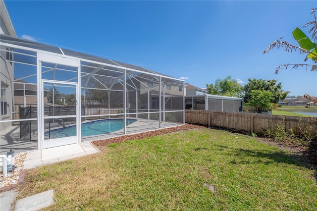 exterior space with a fenced in pool, glass enclosure, fence, and a lawn