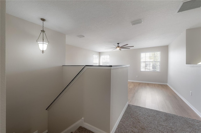 interior space featuring baseboards, visible vents, a textured ceiling, and an upstairs landing