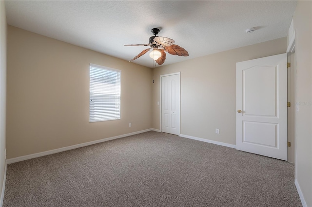 empty room featuring carpet floors, ceiling fan, and baseboards