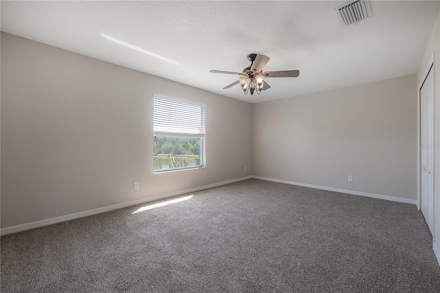 carpeted spare room with baseboards, visible vents, and a ceiling fan