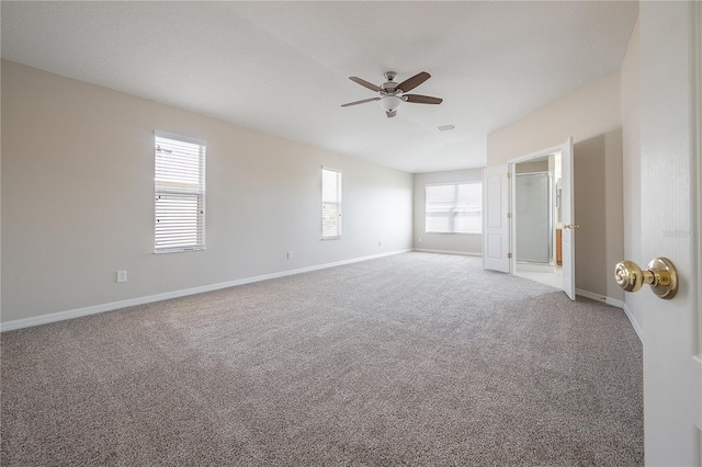 carpeted empty room with visible vents, baseboards, vaulted ceiling, and a ceiling fan