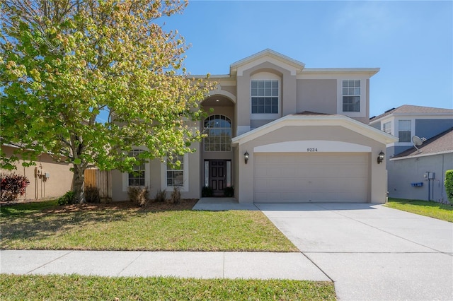 traditional home with driveway, a garage, a front yard, and stucco siding