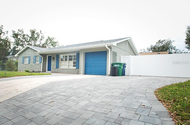 single story home featuring decorative driveway, an attached garage, and fence