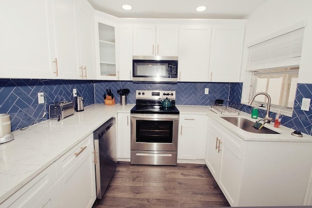 kitchen with dark wood-style floors, stainless steel appliances, glass insert cabinets, white cabinets, and a sink