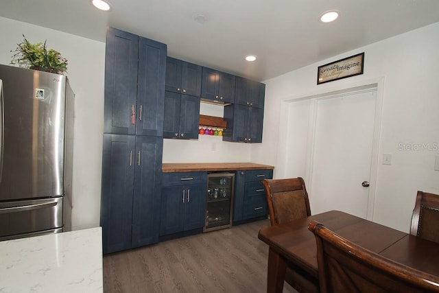 kitchen featuring light wood-style flooring, wine cooler, freestanding refrigerator, blue cabinetry, and recessed lighting