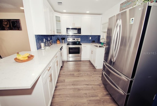 kitchen with tasteful backsplash, visible vents, a peninsula, stainless steel appliances, and light wood-style floors