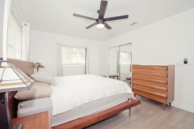 bedroom featuring baseboards, visible vents, a ceiling fan, wood finished floors, and a closet