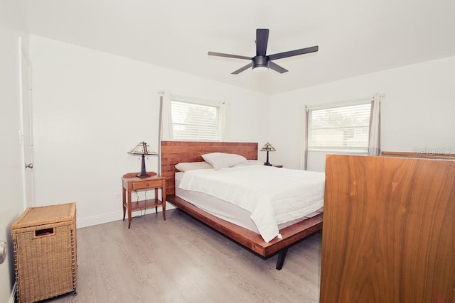 bedroom with light wood finished floors, ceiling fan, multiple windows, and baseboards