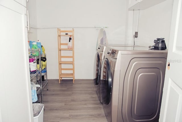 clothes washing area with light wood finished floors, laundry area, and washing machine and clothes dryer