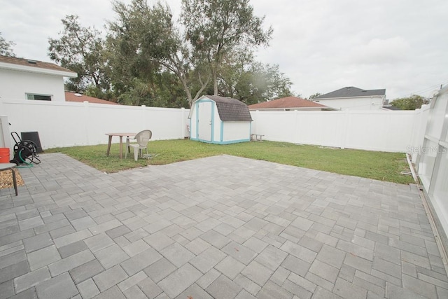 view of patio featuring a fenced backyard, a storage unit, and an outbuilding