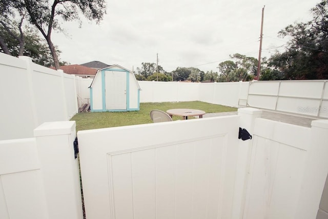 view of yard featuring a storage shed, a fenced backyard, and an outbuilding