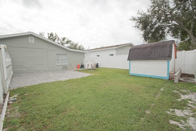 view of yard with a storage shed, a patio, an outbuilding, and a fenced backyard