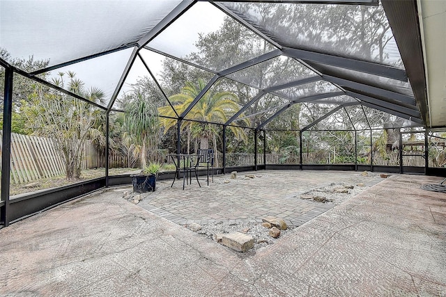 view of patio featuring glass enclosure and fence