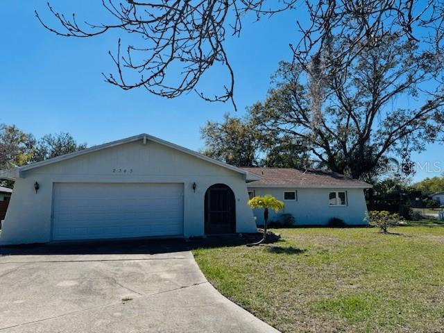 ranch-style house featuring a garage, a front lawn, concrete driveway, and stucco siding