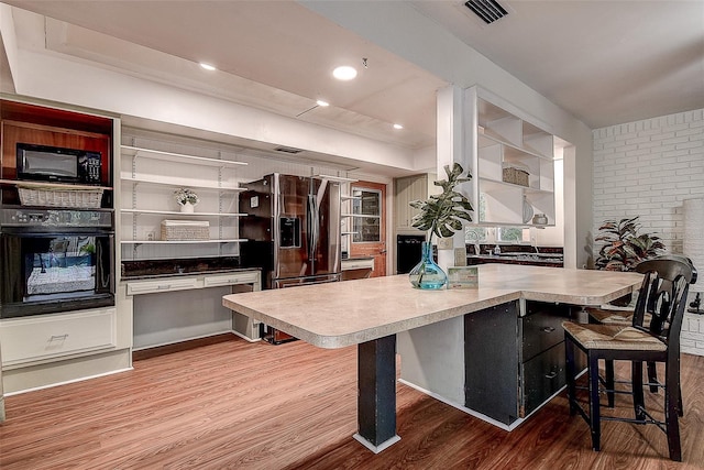 kitchen featuring visible vents, black appliances, and wood finished floors