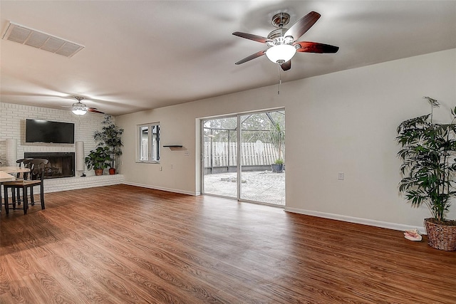 living room with a fireplace, wood finished floors, visible vents, and baseboards