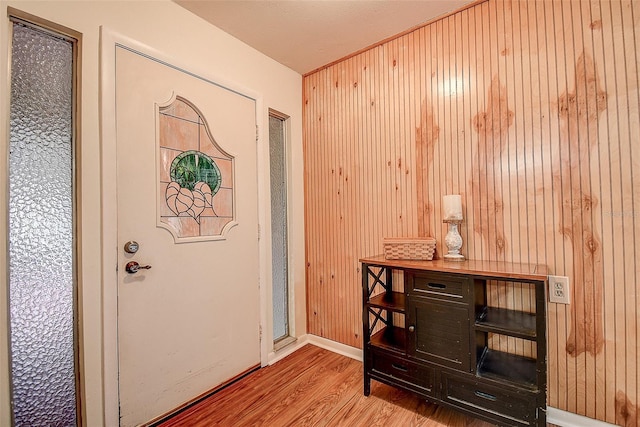 entrance foyer featuring wood walls, baseboards, and wood finished floors