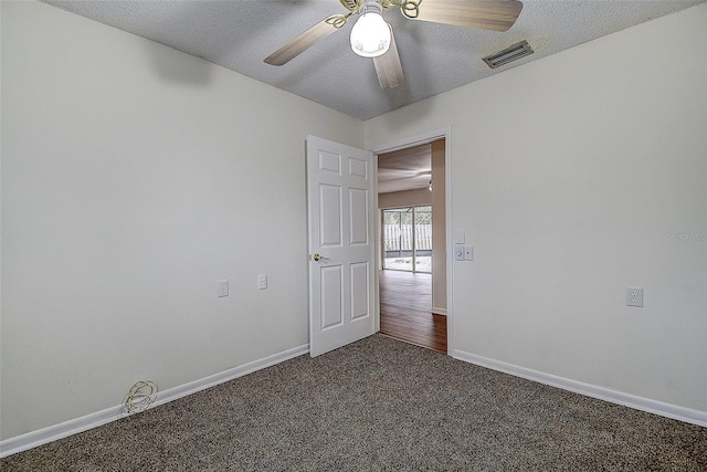 unfurnished room with visible vents, dark carpet, a textured ceiling, and baseboards