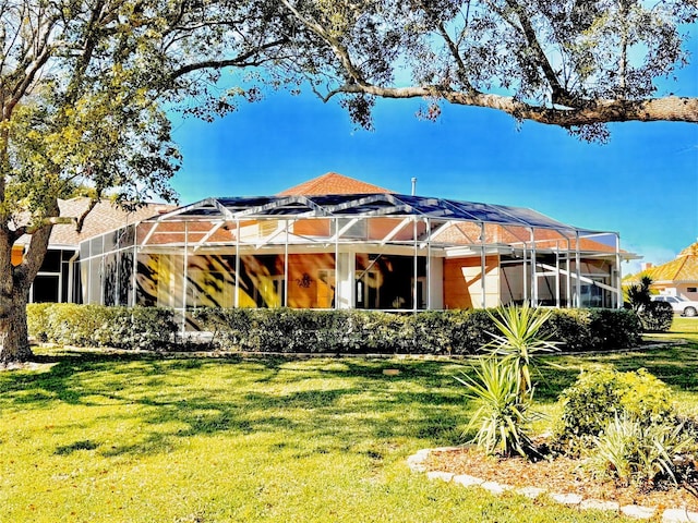 rear view of property with a lanai and a yard