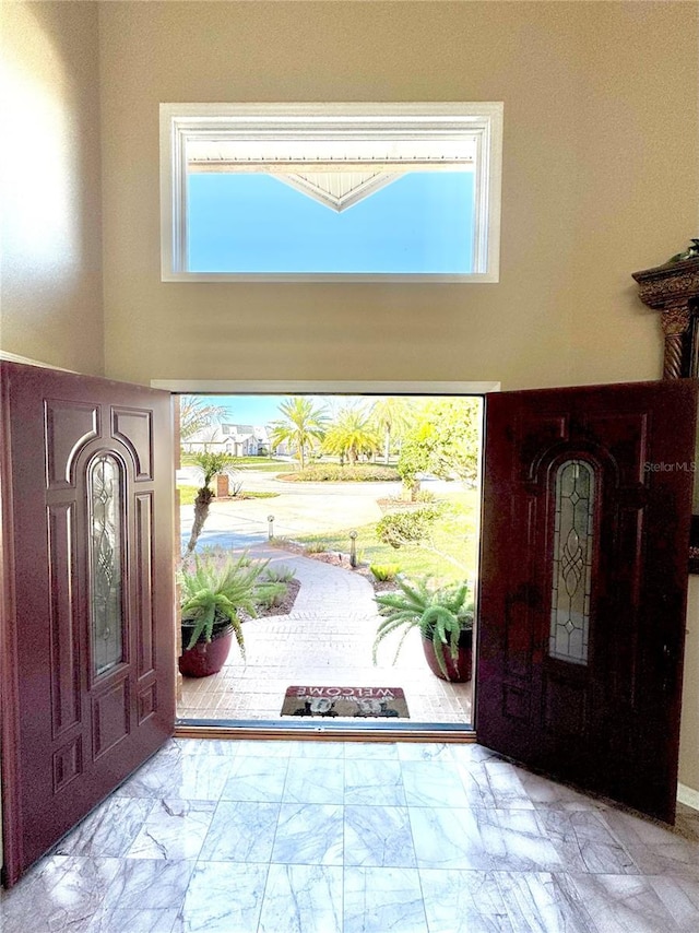 foyer entrance featuring marble finish floor and a high ceiling