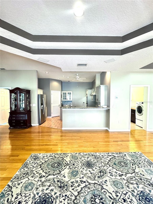 living area featuring light wood-style floors, visible vents, washer / clothes dryer, and a textured ceiling