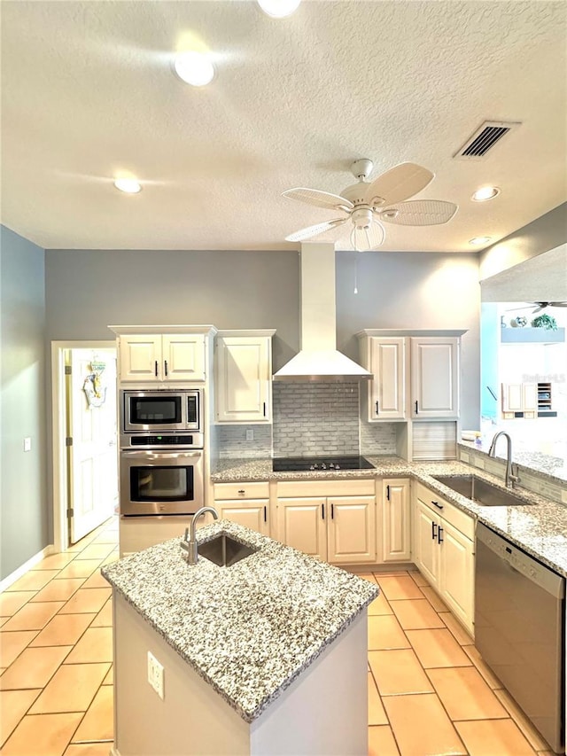 kitchen with stainless steel appliances, wall chimney range hood, a sink, and visible vents