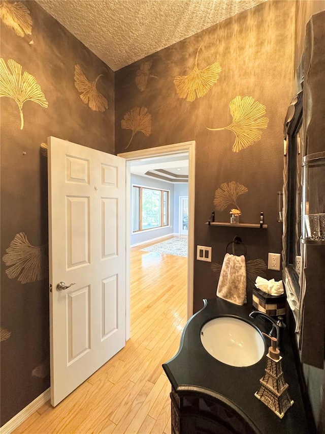 bathroom featuring baseboards, a sink, a textured ceiling, and hardwood / wood-style floors