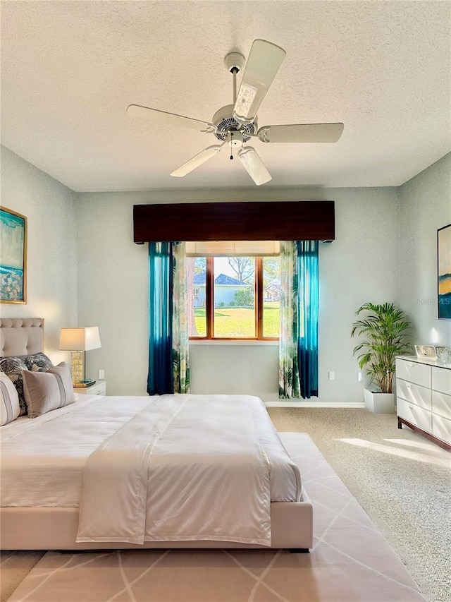 carpeted bedroom featuring ceiling fan, baseboards, and a textured ceiling