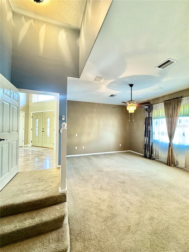 interior space with visible vents, ceiling fan, a textured ceiling, and baseboards