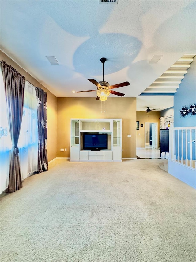 unfurnished living room with visible vents, carpet flooring, ceiling fan, a textured ceiling, and baseboards