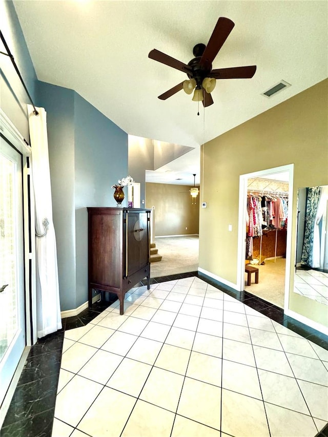 spare room with vaulted ceiling, a wealth of natural light, tile patterned flooring, and visible vents