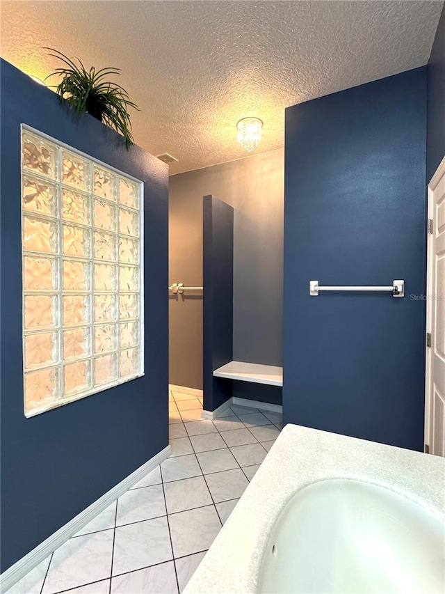 bathroom with tile patterned flooring, a textured ceiling, baseboards, and a sink