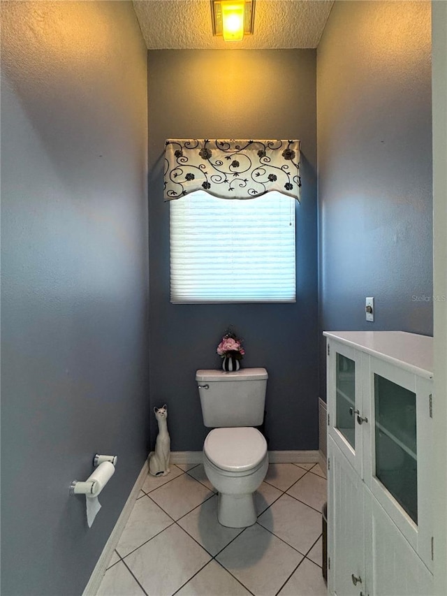 bathroom featuring baseboards, a textured ceiling, toilet, and tile patterned floors