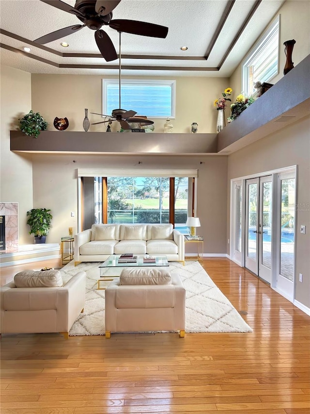 living room with hardwood / wood-style flooring, plenty of natural light, a high ceiling, and a tray ceiling