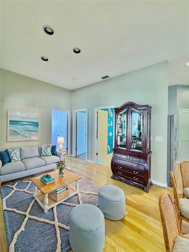 living area featuring light wood-style floors, recessed lighting, visible vents, and baseboards