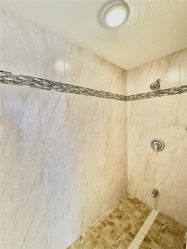 details with a tile shower and a textured ceiling