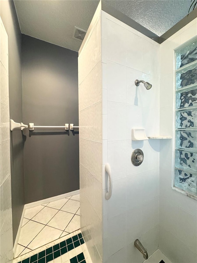 bathroom featuring a textured ceiling, visible vents, and tiled shower