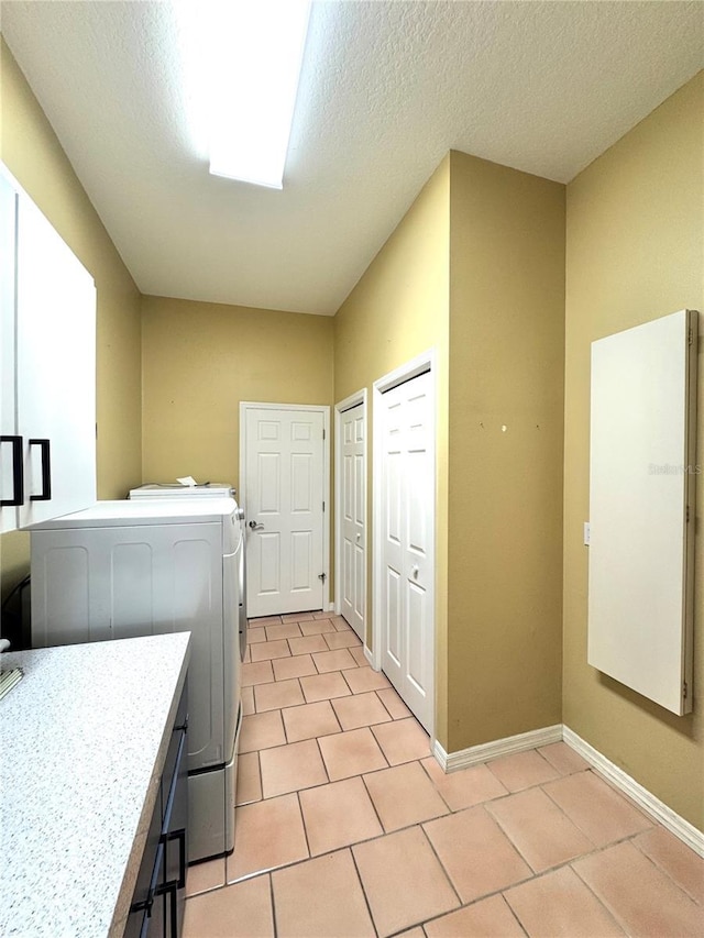 washroom with light tile patterned floors, laundry area, a textured ceiling, and baseboards