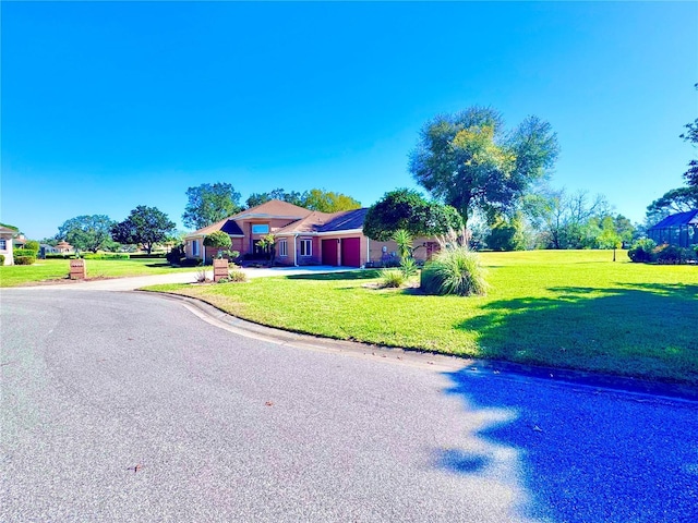 view of front of home with an attached garage, concrete driveway, and a front yard