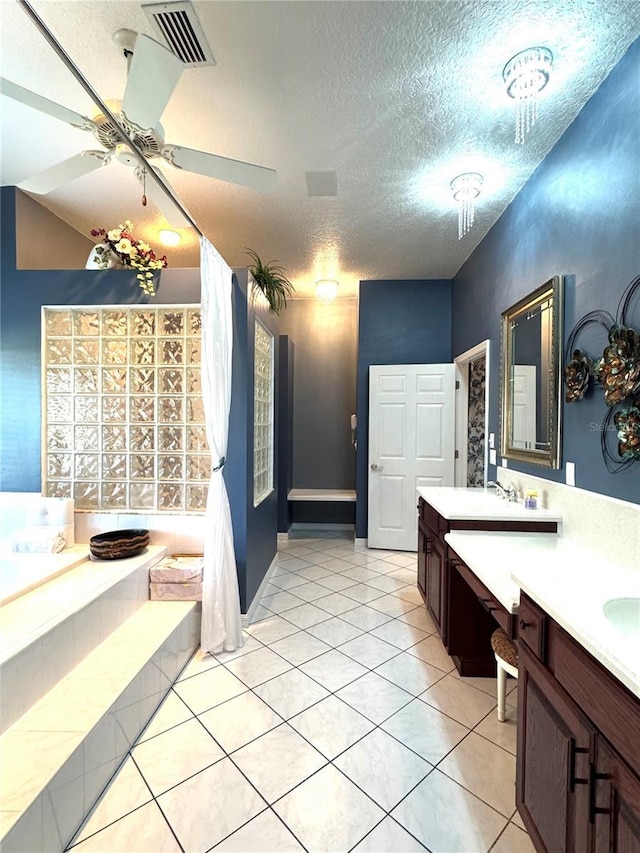 bathroom with visible vents, tile patterned floors, a garden tub, a textured ceiling, and two vanities