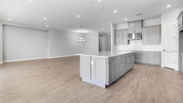 5646 Nevis Ter, Kissimmee, FL 34758 - kitchen featuring gray cabinetry, under cabinet range hood, a chandelier, recessed lighting, and light wood-type flooring
