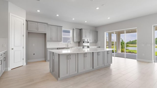 5646 Nevis Ter, Kissimmee, FL 34758 - kitchen featuring gray cabinetry, a kitchen island, light countertops, stainless steel double oven, and recessed lighting