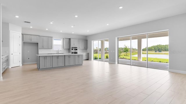 5646 Nevis Ter, Kissimmee, FL 34758 - kitchen with gray cabinets, baseboards, light countertops, recessed lighting, and a kitchen island with sink