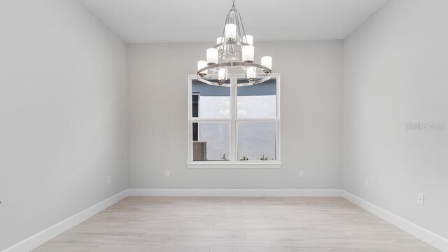 5646 Nevis Ter, Kissimmee, FL 34758 - spare room featuring a chandelier, baseboards, and light wood-style flooring