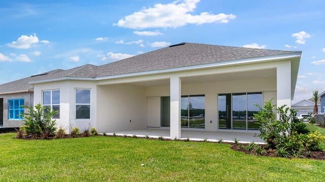 5646 Nevis Ter, Kissimmee, FL 34758 - back of property featuring a yard, a patio, stucco siding, and roof with shingles