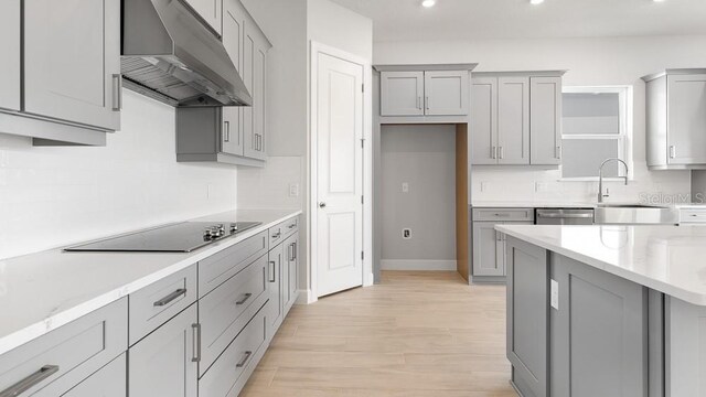 5646 Nevis Ter, Kissimmee, FL 34758 - kitchen with under cabinet range hood, gray cabinetry, black electric cooktop, decorative backsplash, and recessed lighting